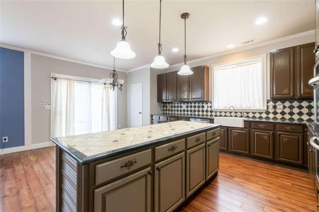 kitchen with pendant lighting, a center island, sink, and dark brown cabinets