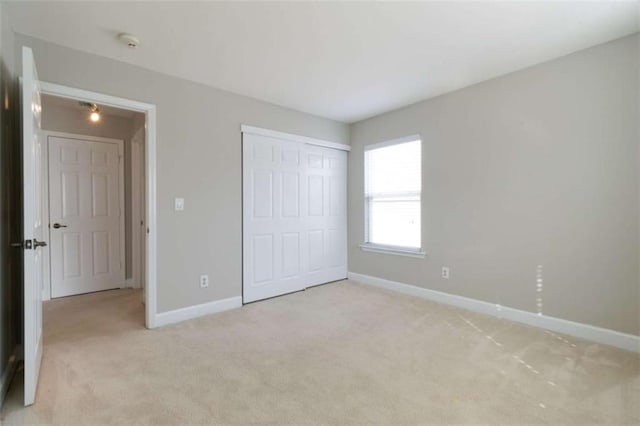 unfurnished bedroom with light colored carpet and a closet