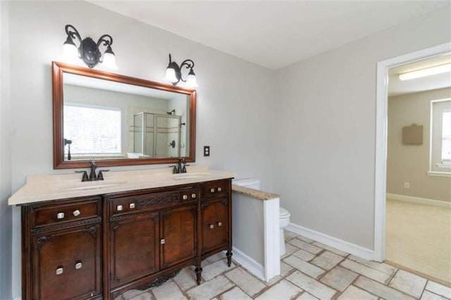 bathroom featuring vanity, a shower with shower door, and toilet