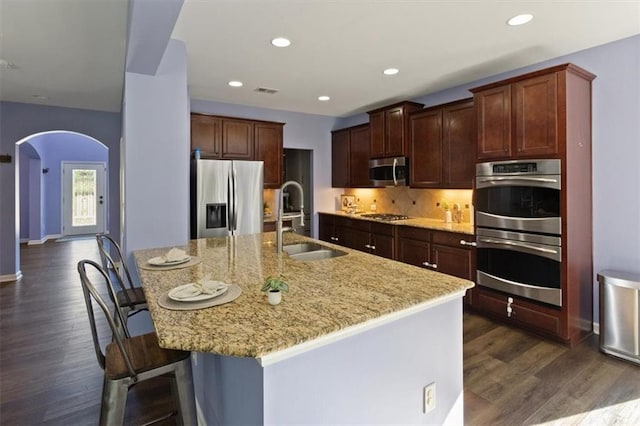 211 Parc Dr, Canton, GA 30114 - kitchen with appliances with stainless steel finishes, a sink, arched walkways, dark wood-style flooring, and light stone countertops