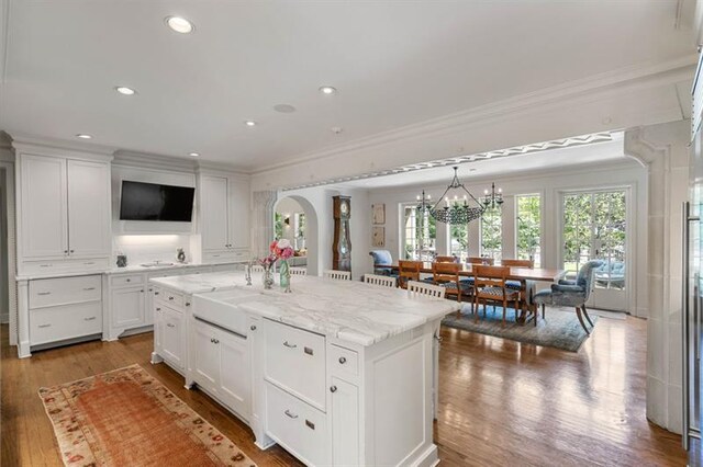 675 W Paces Ferry Rd NW Unit 11, Atlanta, GA 30327 - kitchen with wood finished floors, ornamental molding, light stone counters, a kitchen island with sink, and white cabinets