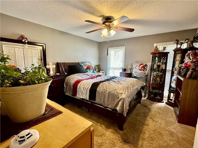 bedroom featuring a textured ceiling, dark carpet, and a ceiling fan