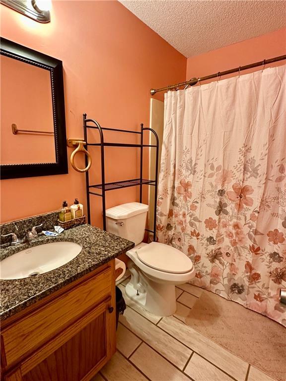 bathroom with toilet, a textured ceiling, and vanity