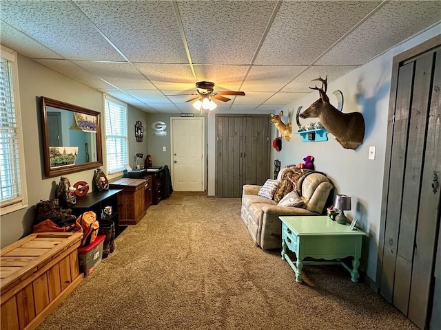 interior space with a paneled ceiling, carpet flooring, and ceiling fan