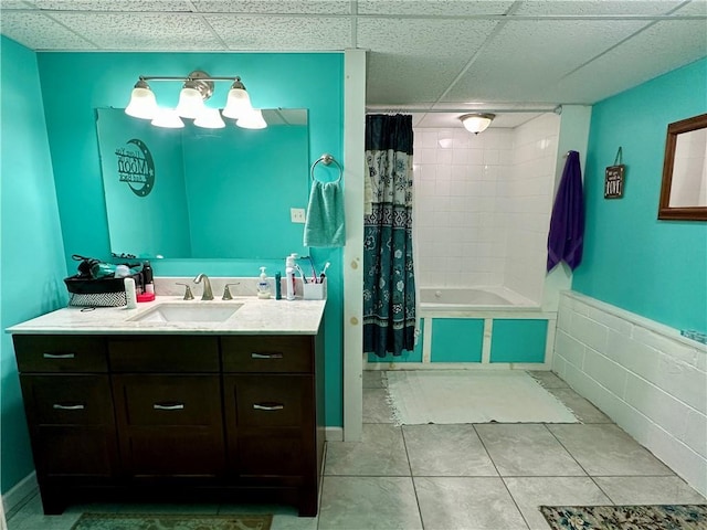 bathroom featuring tile patterned flooring, a paneled ceiling, tiled shower / bath combo, and vanity