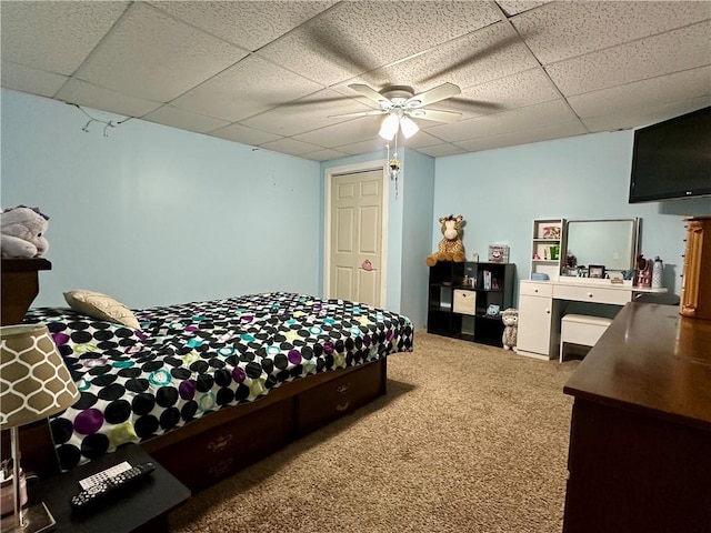 bedroom with ceiling fan, a drop ceiling, and carpet flooring