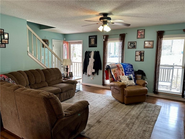 living area with ceiling fan, stairway, plenty of natural light, and wood finished floors