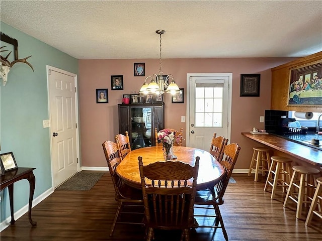 dining room with an inviting chandelier, a textured ceiling, baseboards, and dark wood-type flooring