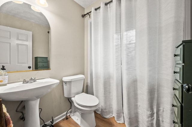 bathroom featuring hardwood / wood-style flooring, toilet, and a textured ceiling