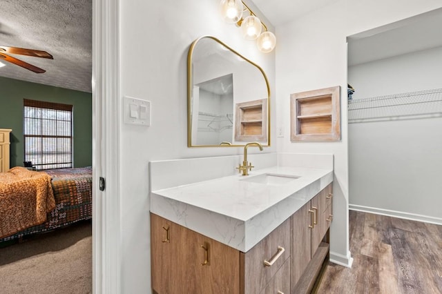 bathroom with vanity, wood-type flooring, ceiling fan, and a textured ceiling