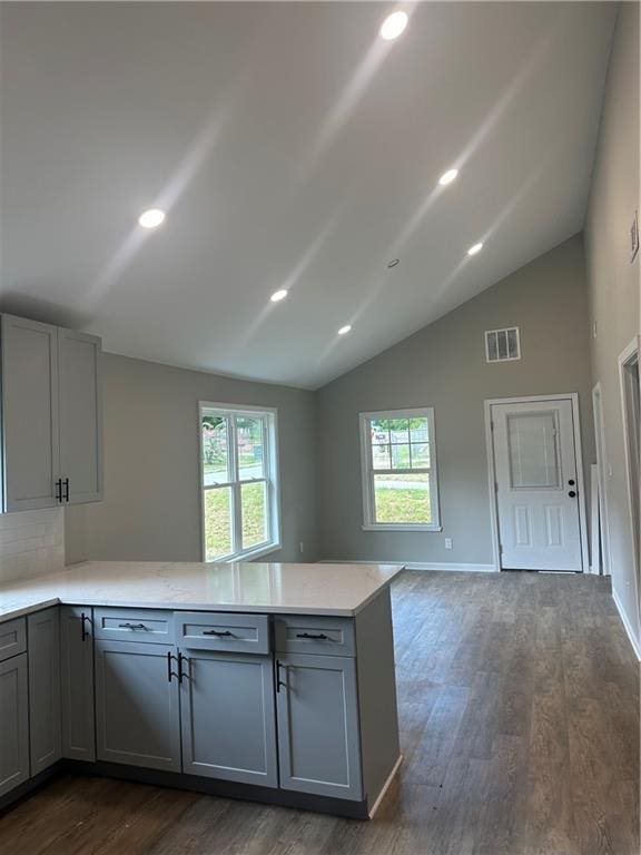 kitchen featuring kitchen peninsula, gray cabinets, dark hardwood / wood-style floors, and vaulted ceiling