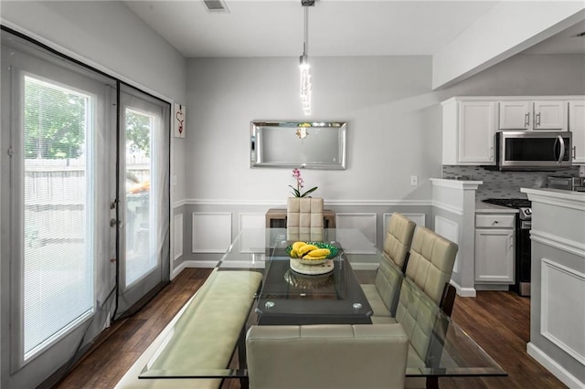 dining area with dark wood-style flooring and a wainscoted wall