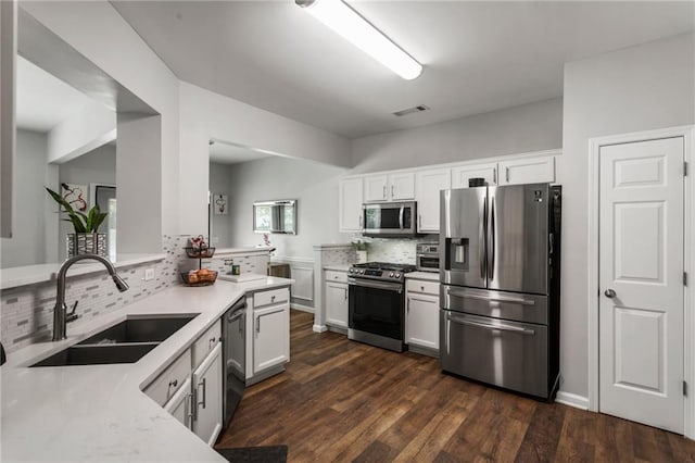 kitchen with dark wood-style flooring, a sink, light countertops, stainless steel appliances, and decorative backsplash