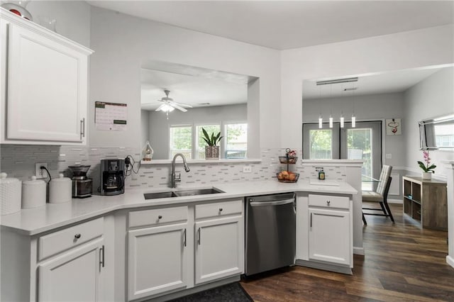 kitchen with tasteful backsplash, dark wood finished floors, dishwasher, a sink, and light countertops