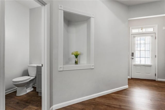 interior space with baseboards, wood finished floors, and toilet