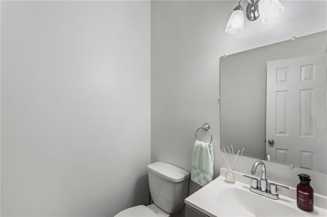 half bath with toilet, a notable chandelier, and vanity