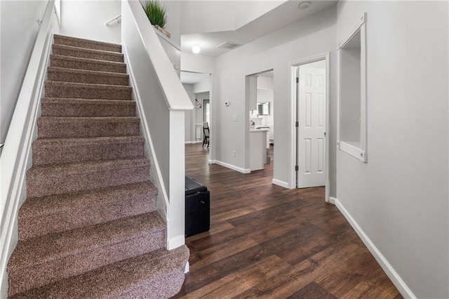 stairs with baseboards, wood finished floors, and visible vents
