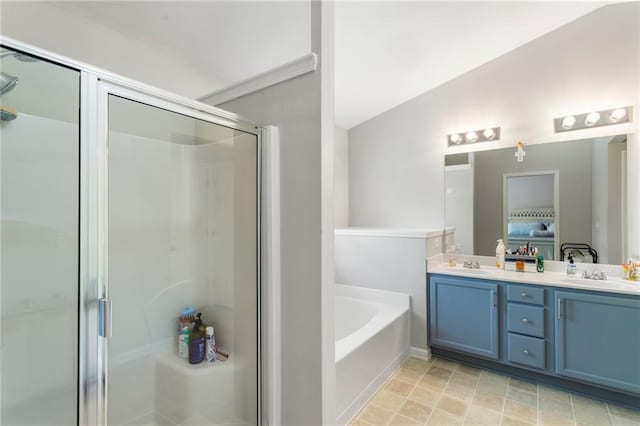 ensuite bathroom with double vanity, a stall shower, a sink, and a bath