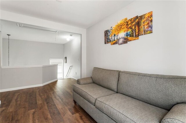 living room featuring baseboards, wood finished floors, and attic access