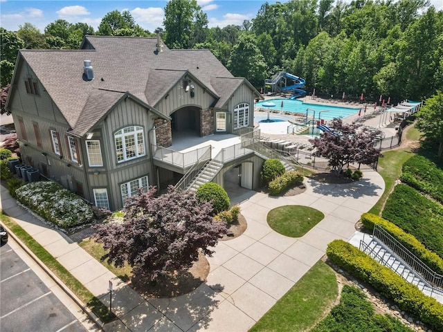 exterior space featuring a shingled roof, board and batten siding, stairway, an outdoor pool, and cooling unit