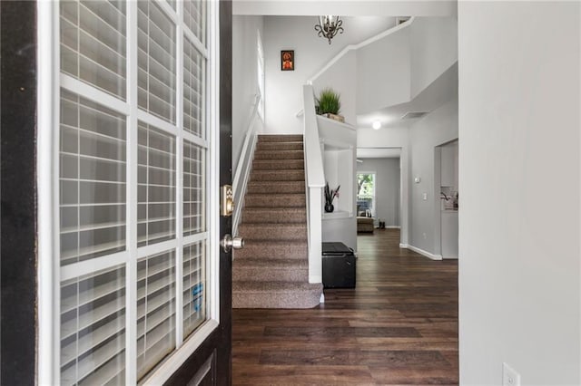 staircase featuring baseboards, visible vents, wood finished floors, and a towering ceiling