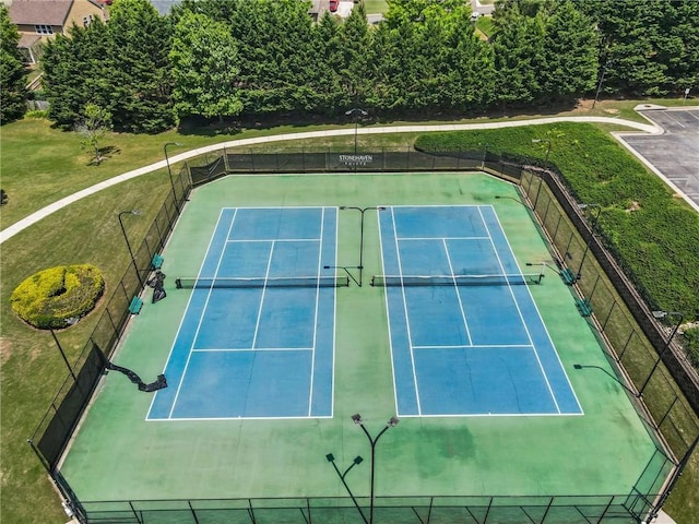 view of tennis court featuring a lawn and fence