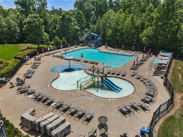 community pool with fence, a water slide, and a water play area