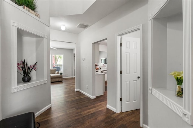 hall with dark wood-type flooring, baseboards, and visible vents
