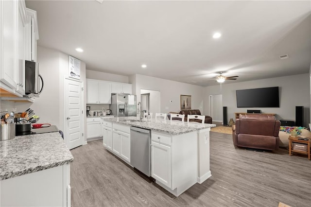 kitchen featuring white cabinets, a center island with sink, stainless steel appliances, and light hardwood / wood-style floors