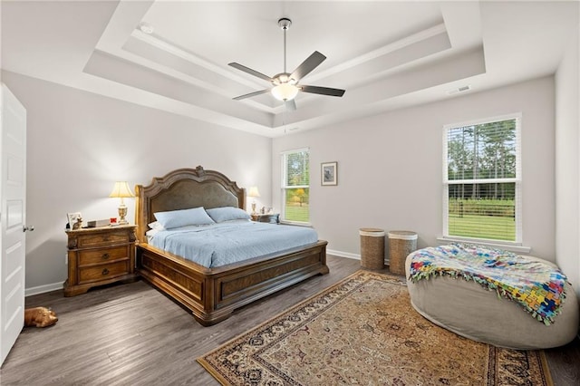 bedroom featuring a raised ceiling, wood-type flooring, and ceiling fan