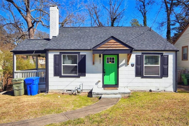 bungalow with a shingled roof, a chimney, and a front yard