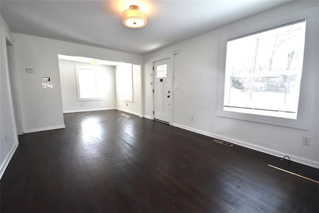 foyer featuring baseboards, visible vents, and wood finished floors