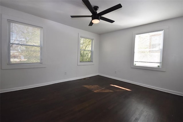 spare room featuring ceiling fan, dark wood-type flooring, a wealth of natural light, and baseboards