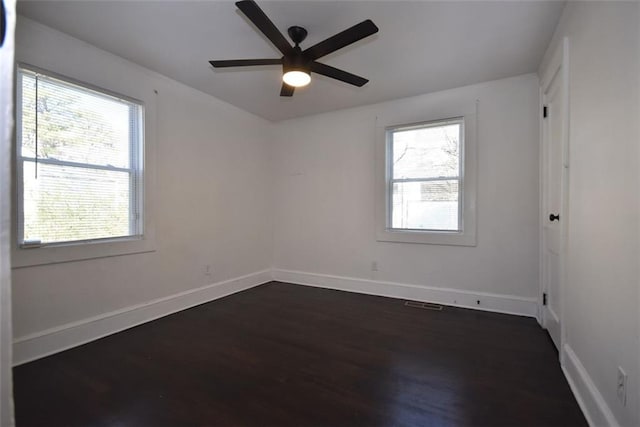 spare room featuring dark wood-type flooring, baseboards, and a ceiling fan