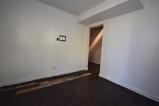 spare room featuring dark wood-style flooring and baseboards