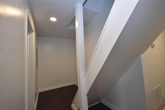 corridor featuring visible vents, baseboards, and wood finished floors