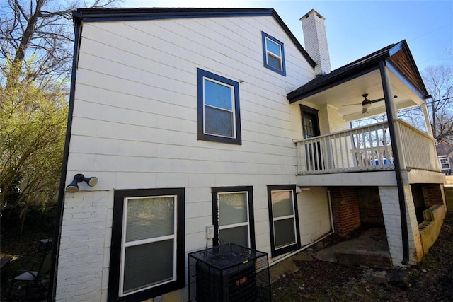 rear view of house with a balcony, a chimney, and a ceiling fan