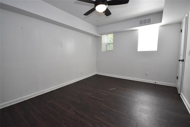 spare room featuring ceiling fan, dark wood finished floors, visible vents, and baseboards