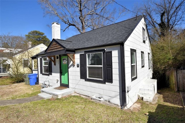 bungalow-style home featuring a front yard, roof with shingles, fence, and a chimney