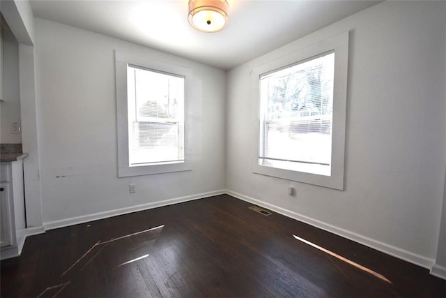 empty room featuring visible vents, baseboards, and wood finished floors