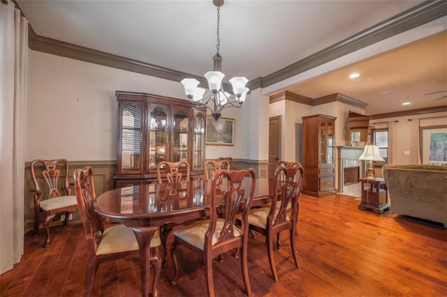 dining area featuring wood-type flooring, crown molding, and an inviting chandelier