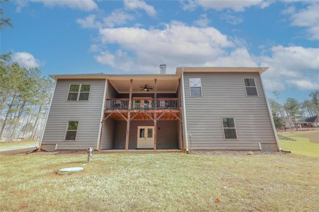 rear view of house featuring ceiling fan, a balcony, and a lawn