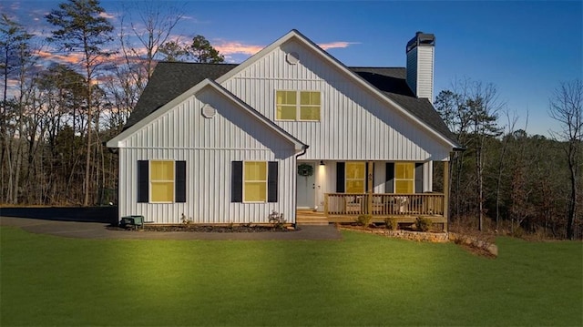 back house at dusk with a yard and covered porch