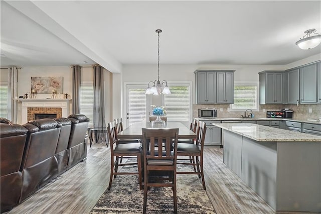 dining area with an inviting chandelier, a fireplace, and wood finished floors