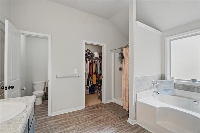 full bath featuring vanity, wood finished floors, toilet, baseboards, and a bath