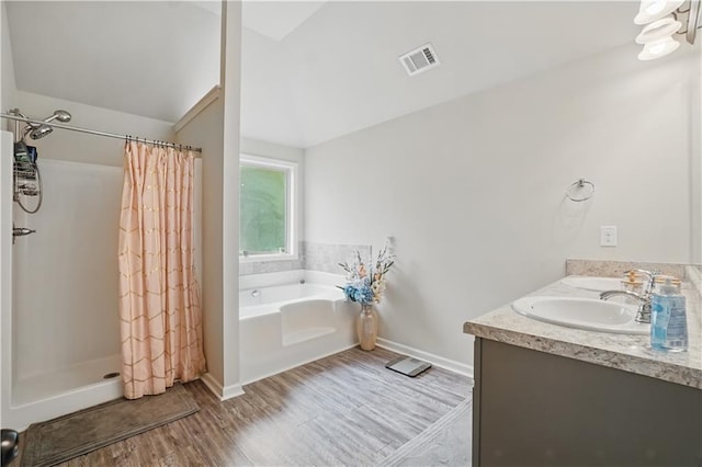 full bath with wood finished floors, vaulted ceiling, visible vents, a bath, and a stall shower