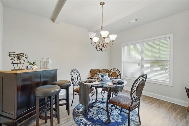 dining room with a notable chandelier, light wood-style flooring, baseboards, beamed ceiling, and visible vents