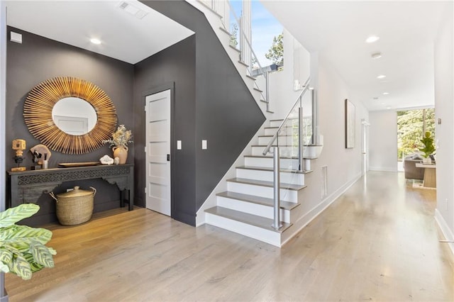 stairway with recessed lighting, wood finished floors, visible vents, and baseboards