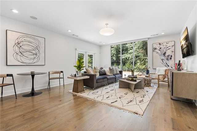 living room featuring recessed lighting, baseboards, visible vents, and light wood finished floors