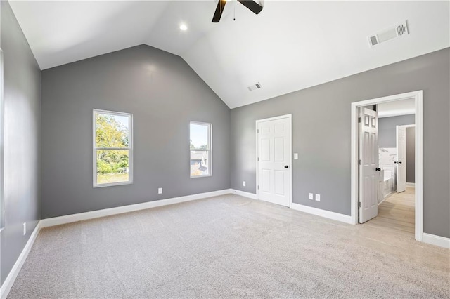 unfurnished bedroom featuring lofted ceiling, light colored carpet, connected bathroom, and ceiling fan